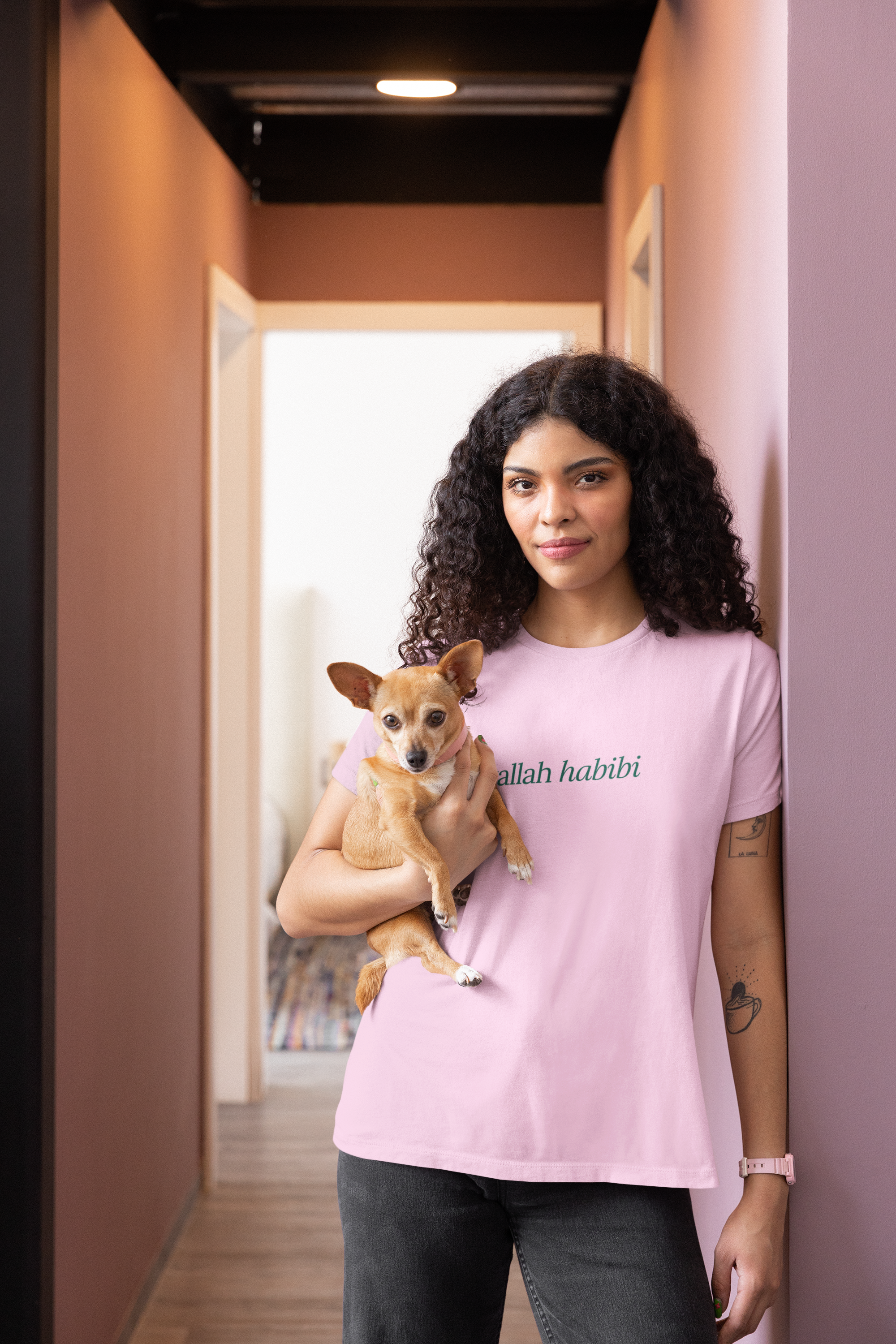 tee mockup of a woman with curly hair carrying her puppy, showcasing a cozy and casual look. Perfect for dog lovers and relaxed, everyday fashion
