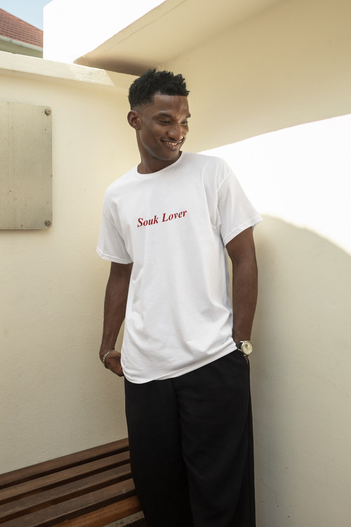 Man wearing white T-shirt with ‘Souk Lover’ text in red, standing by a wall